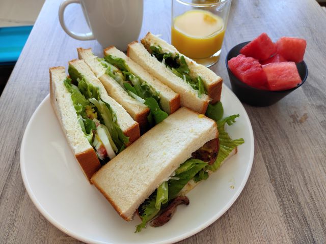 コンドでの食事、朝食に作ったボリュームサンドイッチとジュース・フルーツの写真