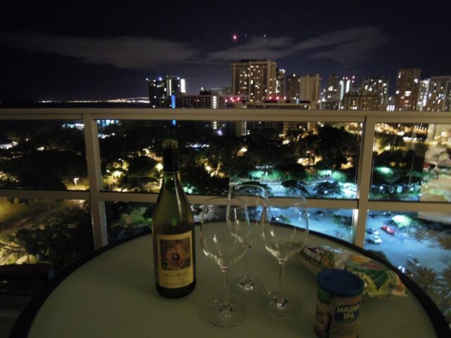 ホテルのラナイでワイキキの夜景を見ながらワインとおつまみを楽しむ写真